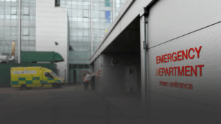 The front of an emergency department with an ambulance in the background